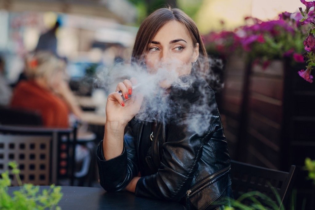 woman using vaping product outdoors