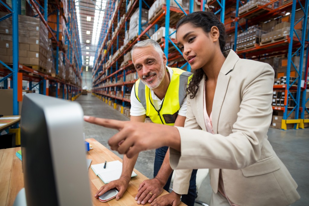 man and woman in a warehouse looking at a computer