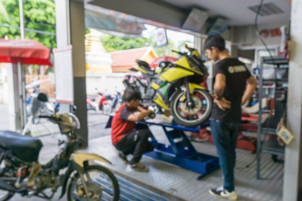 Blurred of motorcycle technician repairing the motorcycle in garage background.