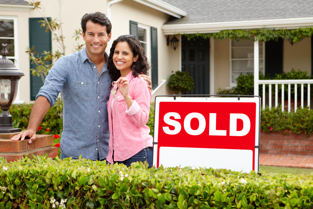 couple beside a sold sign in front of a new house