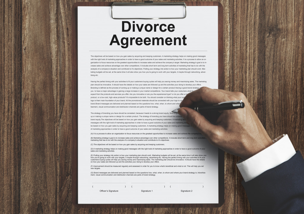 A divorce agreement document with a hand signing on it