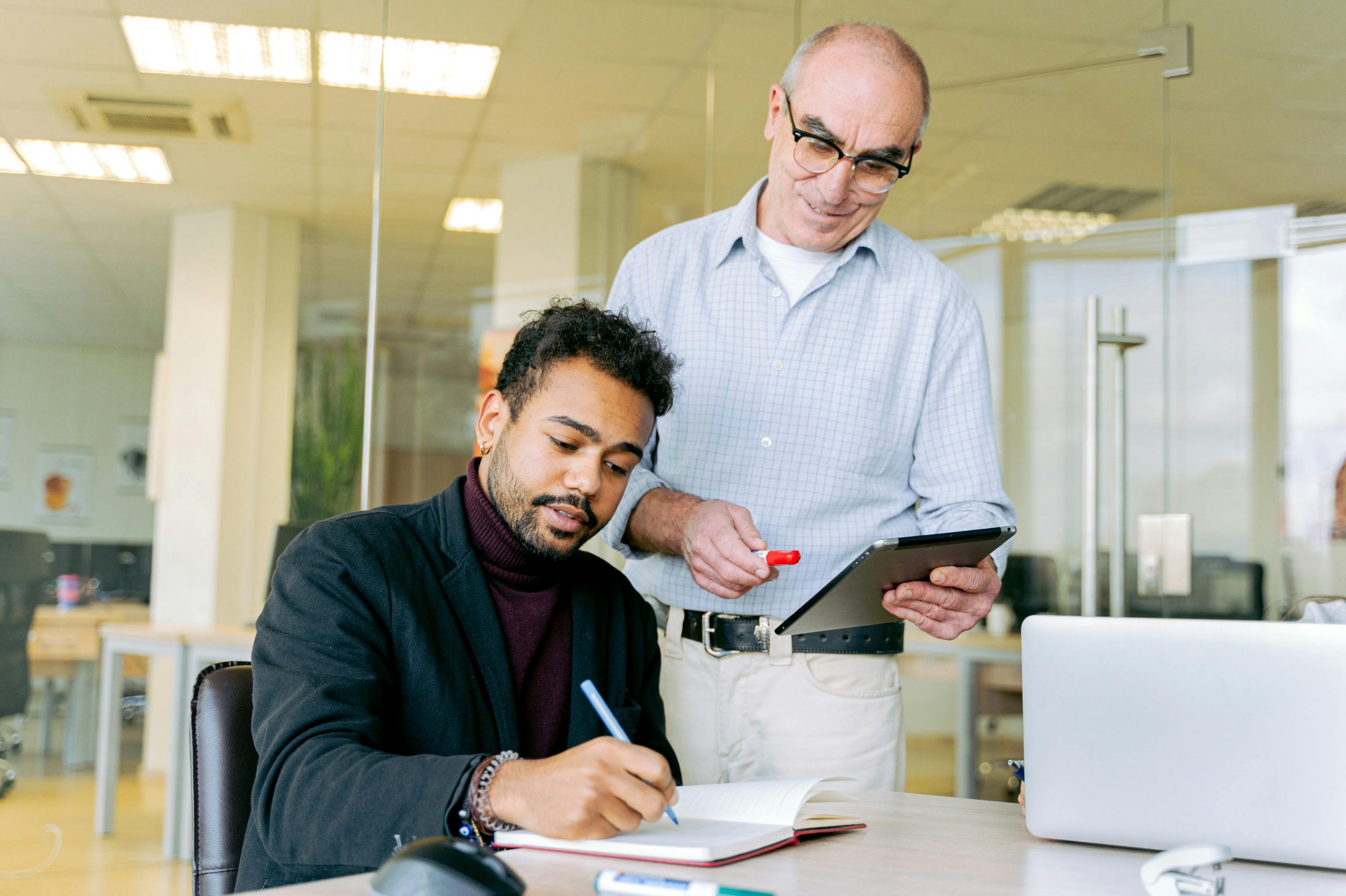 manager giving feedback to a focused employee who is taking notes