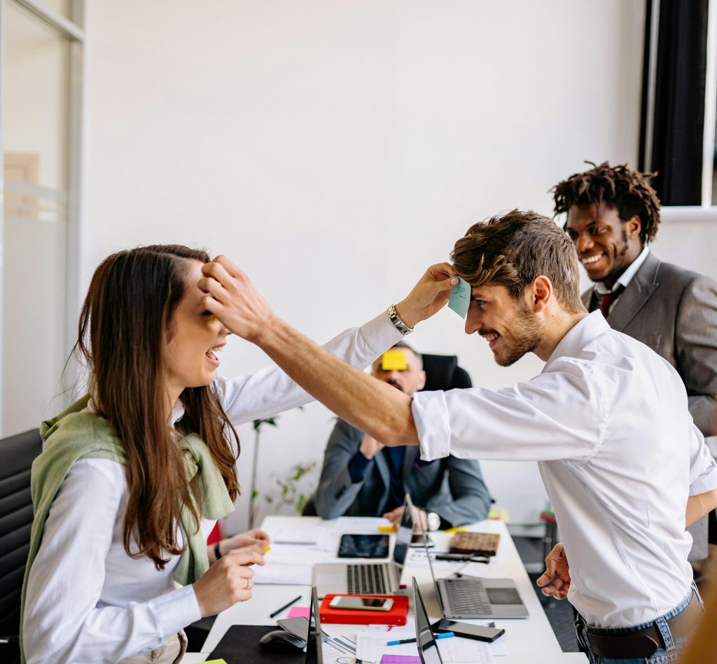 employees laughing while playing a game with Post-it notes on their foreheads